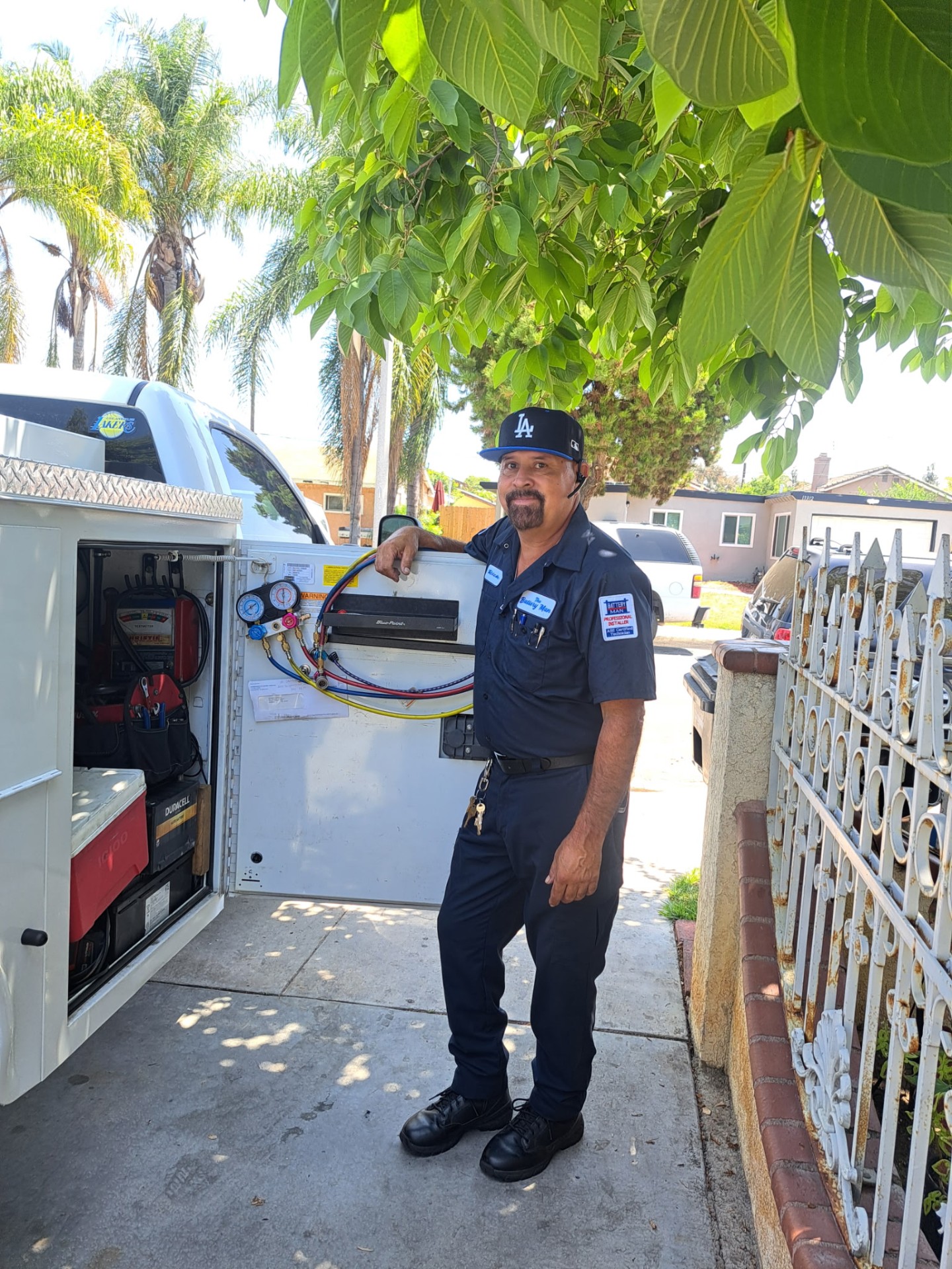 Rick standing at his open service truck with A/C gauges and battery tools inside